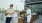 a couple of men standing next to a grill with food on it